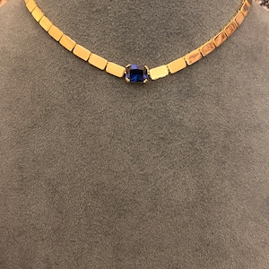 May include: A gold chain necklace with a blue gemstone pendant.