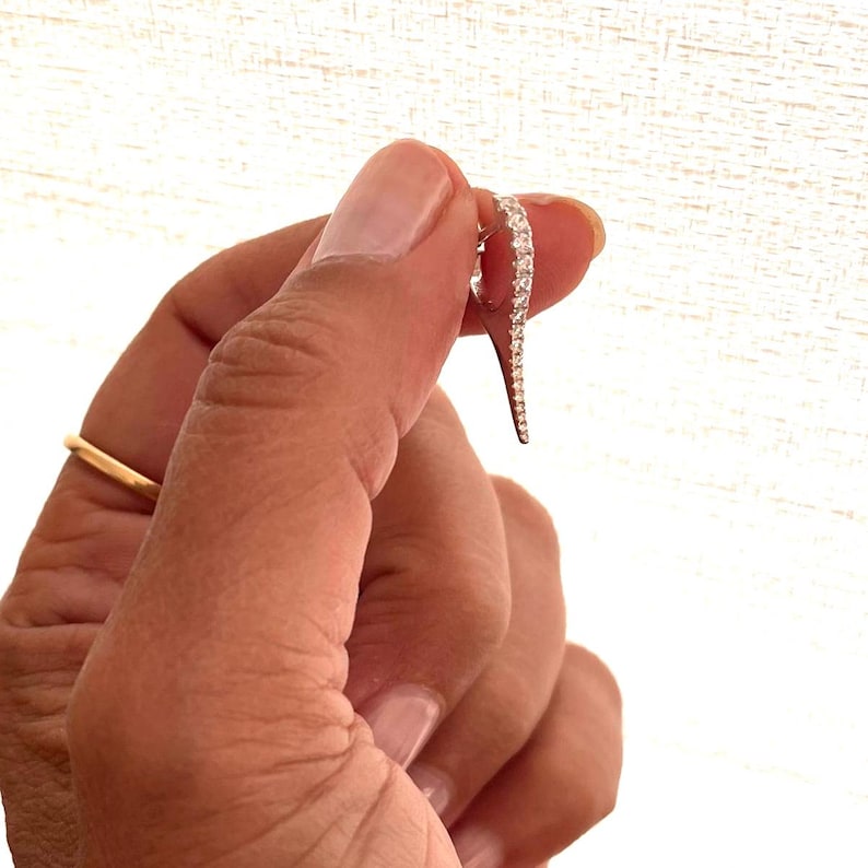 May include: A silver ring with a curved design and a row of small, clear stones.