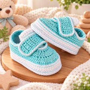 May include: A pair of handmade crochet baby shoes in a bright turquoise color with white trim. The shoes feature a low-top sneaker design with a rounded toe, a textured yarn finish, and a single strap closure across the top of the foot.