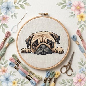 May include: A round wooden embroidery hoop containing a fabric panel with a cross-stitch design of a tan pug dog face. The hoop is surrounded by several colorful embroidery floss skeins, a metal needle, and vintage-style metal scissors.
