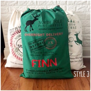 May include: Green Christmas gift bag with a white reindeer and the text "North Pole Post Office" and "Overnight Delivery". The bag has a red and white striped border and the name "Finn" is written in red.
