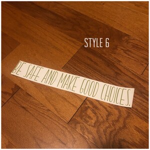 May include: A white sticker with the text "BE SAFE AND MAKE GOOD CHOICES." in green lettering on a wood floor. The text "STYLE 6" is written in black above the sticker.