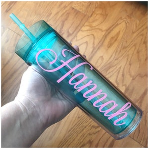 May include: A clear, turquoise tumbler with a pink vinyl decal that says "Hannah" and a clear lid with a straw.