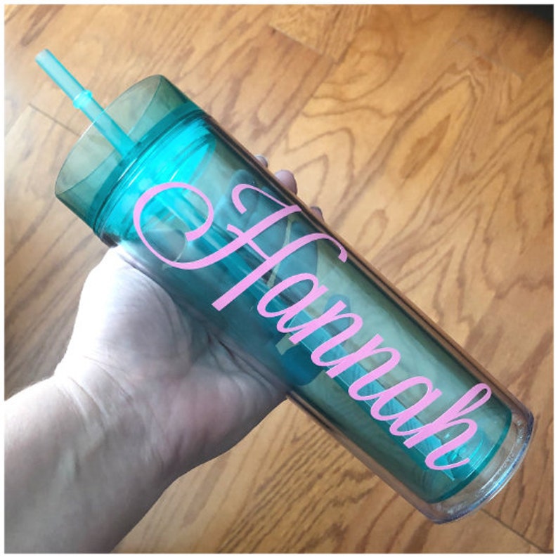 May include: A clear, turquoise tumbler with a pink vinyl decal that says "Hannah" and a clear lid with a straw.