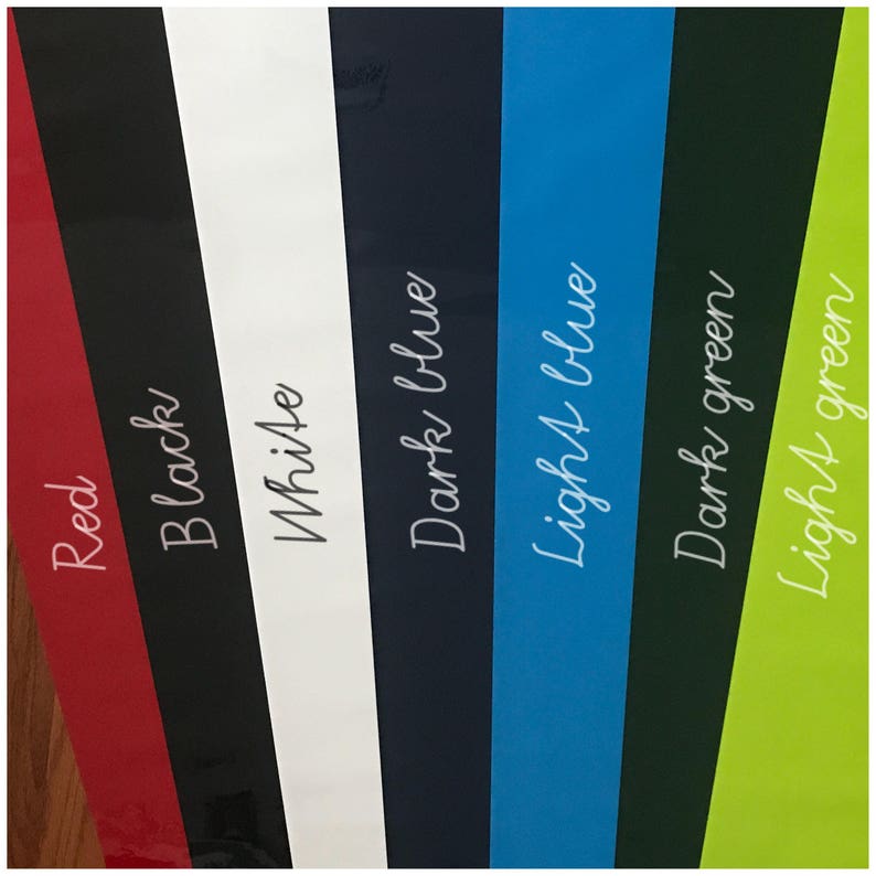 May include: A close-up of six different colored fabric swatches. The swatches are arranged from left to right: red, black, white, dark blue, light blue, dark green, and light green.