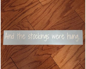 May include: A white vinyl decal with the text "And the stockings were hung..." on a light blue background.