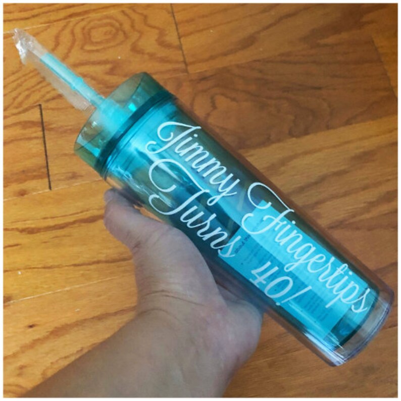 May include: A turquoise blue tumbler with a white straw and the text "Jimmy Fingertips Turns 40!" in white cursive lettering.
