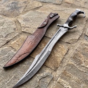 May include: A Damascus steel sword with a curved blade and a dark handle, accompanied by a brown leather sheath featuring a stamped helmet design and metal rivets. The blade displays a distinct wavy pattern, and the hilt has a hooked pommel.