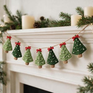 May include: A garland featuring seven crocheted Christmas tree ornaments in alternating shades of light and dark green. Each tree is topped with a small red yarn bow and decorated with tiny white beads, all strung together on a thin twine cord.