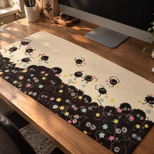 Può includere: Un tappetino da scrivania rettangolare con sfondo color crema e un denso gruppo di personaggi neri, rotondi e pelosi nella parte inferiore. Tra le figure sono sparse piccole stelle colorate a più punte nei toni del rosa, giallo e azzurro.