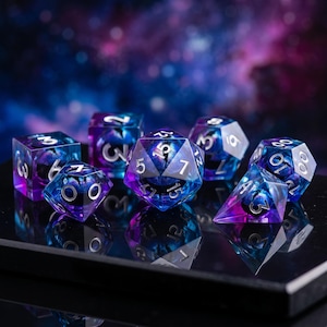 May include: A set of seven polyhedral dice featuring a translucent blend of deep purple and vibrant blue colors. Each die has sharp edges and is marked with clear, silver-colored numbers. The dice are arranged on a reflective black surface.