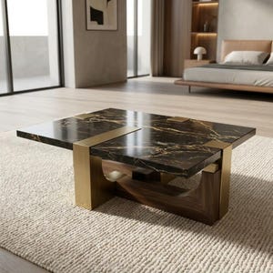 Op de afbeelding: Een rechthoekige salontafel met een zwart marmeren blad met gouden aders. De tafel rust op een onderstel van donker hout, geaccentueerd met geborstelde goudkleurige metalen beugels die om de randen van het marmeren oppervlak heen grijpen.