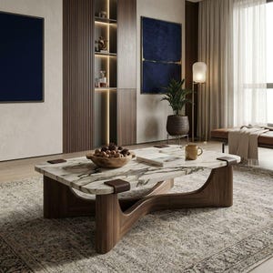 May include: A rectangular coffee table featuring a white marble top with grey veining, supported by a dark brown wooden base with curved, fluted legs and dark leather-wrapped corner accents, holding a wooden bowl of walnuts and a book.