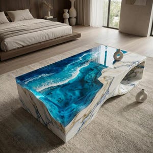 Peut inclure: Une table basse rectangulaire dotée d'une base en marbre blanc aux veines grises et d'une incrustation centrale en résine bleue translucide imitant l'aspect des vagues avec des détails d'écume blanche le long des bords de l'eau bleue.
