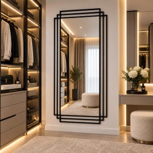 Può includere: Uno specchio da parete alto e rettangolare con una cornice in metallo nero dal design geometrico a strati. Il design è composto da diversi contorni rettangolari sovrapposti che creano un aspetto strutturato e multidimensionale sulla parete.