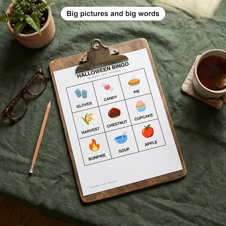 May include: A Halloween Bingo game sheet on a wooden clipboard featuring a 3x3 grid with illustrations and labels for gloves, candy, pie, harvest, chestnut, cupcake, bonfire, soup, and apple. The text reads Big pictures and big words.