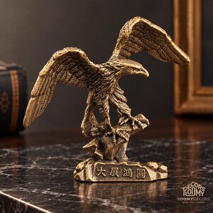 Peut inclure: Une figurine d'aigle couleur bronze aux ailes déployées, perchée sur une base rocheuse. La base présente les caractères chinois 大展鴻圖 gravés sur le devant. La sculpture a une finition métallique texturée et représente l'oiseau en plein vol.