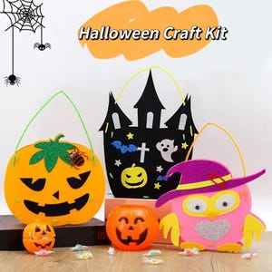 May include: A Halloween craft kit featuring three felt bags: an orange pumpkin, a black haunted house, and a pink owl with a purple hat. Two small plastic orange jack-o'-lantern containers sit in front, surrounded by scattered colourful sweets.