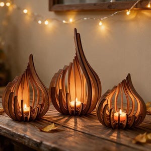 May include: Three flame-shaped candle holders crafted from curved wooden slats. Each holder features a central tea light candle emitting a warm glow. The structures are arranged in a row, showcasing a natural wood grain finish and open design.