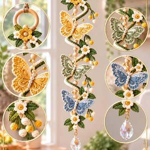 Op de afbeelding: Een verticale macramé wandhanger met drie gehaakte vlinders in geel, groen en blauw, geaccentueerd met witte bloemen, groene bladeren en houten kralen. Het object hangt aan een houten ring en is afgewerkt met een heldere kristallen druppel.