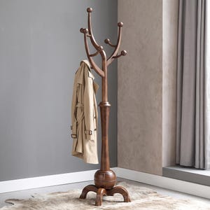 May include: A tall, dark brown wooden coat rack with a central post, a rounded base, and four curved legs. The upper section features multiple branching arms with rounded knobs for hanging items. A beige trench coat hangs from one of the arms.