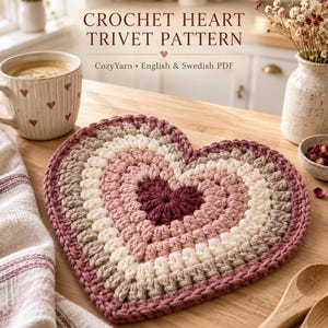 Könnte beinhalten: Ein herzförmiger Häkeluntersetzer mit konzentrischen Garnschichten in den Farben Dunkelrot, Hellrosa, Creme und Beige. Der Text CROCHET HEART TRIVET PATTERN CozyYarn English & Swedish PDF ist über dem Untersetzer abgebildet.