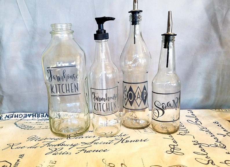 May include: Four clear glass bottles with black labels. The labels say "Farmhouse Kitchen", "Soap", and "Soap".
