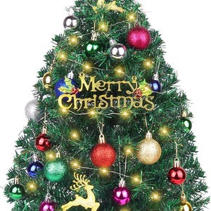 May include: A green artificial Christmas tree decorated with colorful ornaments, gold reindeer figures, and a gold star topper. The tree features a gold sign that reads Merry Christmas and is illuminated by string lights, with gift boxes at the base.
