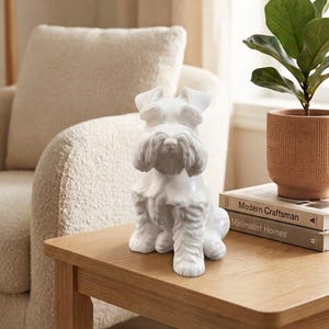 Könnte beinhalten: Eine weiße Keramikfigur eines Schnauzers in aufrechter Sitzposition. Die Skulptur zeigt detaillierte, modellierte Fellstrukturen, spitze Ohren und einen ausgeprägten bärtigen Fang, die das charakteristische Aussehen der Rasse einfangen.
