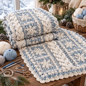 May include: A folded crochet blanket featuring a pattern of white snowflake motifs on a light blue background, accented with thick white cable-knit style borders. The blanket has a scalloped edge and is crafted from soft yarn in winter colors.