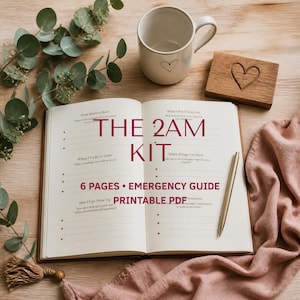 May include: An open journal with printed prompts including What Matters Most, What I Need From You, Where I'd Like to Grow, and When Things Get Hard. The text THE 2AM KIT 6 PAGES EMERGENCY GUIDE PRINTABLE PDF is centered. A gold pen, mug, and wood block with a heart are present.