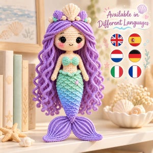 Puede incluir: Una muñeca sirena de ganchillo con largo cabello de lana morada, piel color crema y una cola degradada que pasa de verde menta a azul y morado. La muñeca lleva una corona y un top de conchas. Texto: Available in Different Languages.