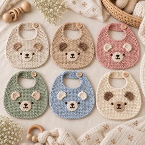 Può includere: Un set di sei bavaglini per neonati all'uncinetto in vari colori tra cui crema, beige, rosa, verde salvia e azzurro. Ogni bavaglino presenta un design a forma di muso d'orso con due piccole orecchie e una chiusura con bottone in legno sul collo.