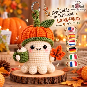 May include: A crochet keychain featuring a cream-colored ghost wearing an orange pumpkin hat with a green stem and leaf. The ghost holds a green mug and an orange maple leaf. Text reads: Available in Different Languages, YarnMallowDesign.