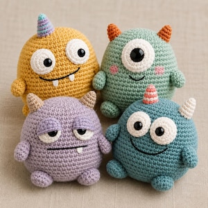 May include: Four round, crocheted monster plushies in yellow, light green, purple, and teal. Each features unique details like small horns, large white eyes with black pupils, and stitched mouths. The yellow one has a single horn, the green one has one eye, the purple one has sleepy eyes, and the teal one has a striped horn.