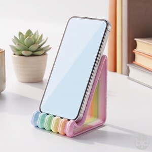 May include: A smartphone resting on a triangular stand featuring a pastel rainbow gradient. The stand has a textured, scalloped front edge with alternating colors of light blue, green, yellow, orange, and pink, supporting the device upright.