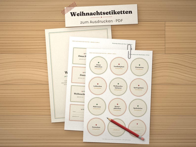 May include: A set of printable PDF sheets labeled "Weihnachtsetiketten zum Ausdrucken - PDF" featuring various circular and rectangular labels with German text, a silver paperclip, and a red pencil resting on the top sheet.
