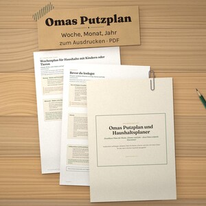 May include: A set of printed cleaning schedule documents titled Omas Putzplan, featuring weekly, monthly, and yearly planning sections. The papers are held together with a metal paperclip, accompanied by a pencil on a wooden surface.