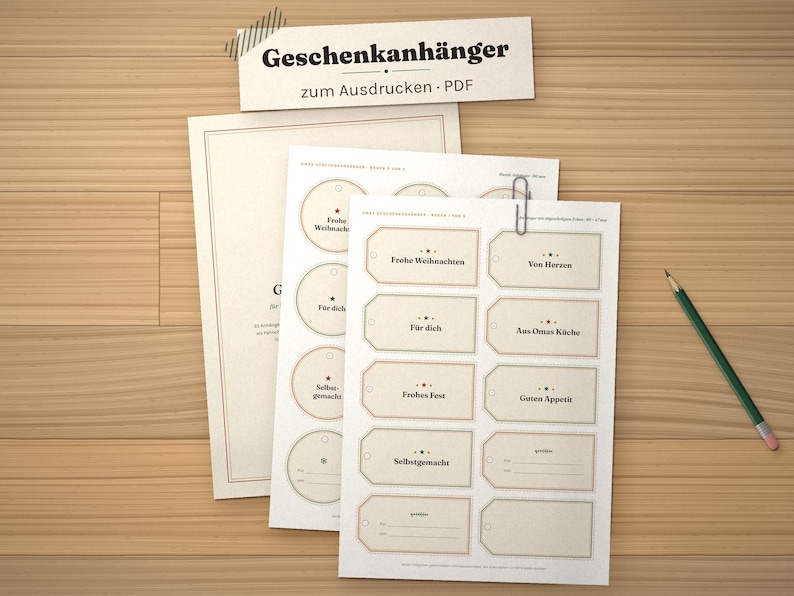 May include: A set of printable gift tags on white paper sheets featuring various rectangular and circular designs with German text including Frohe Weihnachten, F&uuml;r dich, and Selbstgemacht, accompanied by a green pencil and a metal paper clip.