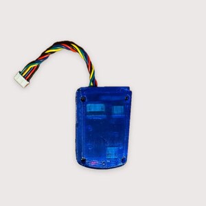 May include: A rectangular blue translucent plastic electronic housing unit with four visible corner screws. A multi-colored ribbon cable consisting of red, yellow, green, blue, and black wires extends from the top, ending in a white plastic connector.
