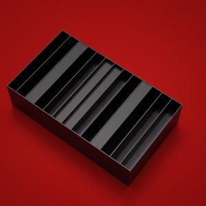 Pode incluir: Um organizador de armazenamento retangular preto com múltiplos divisores verticais paralelos que criam vários compartimentos longos e estreitos. A estrutura é aberta no topo, exibindo um design uniforme e limpo com bordas nítidas e acabamento fosco.