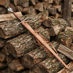 Puede incluir: Una espada larga con pomo y guarda de metal plateado, empu&ntilde;adura forrada en cuero marr&oacute;n y una vaina de cuero marr&oacute;n a juego que presenta correas de cuero integradas y una contera de metal en el extremo puntiagudo de la funda.