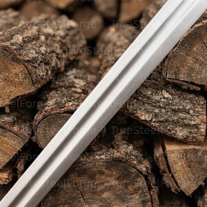 Puede incluir: Una hoja de metal larga, recta y de color plateado que presenta un surco o acanaladura central distintiva a lo largo de su extensi&oacute;n. La superficie del metal tiene un acabado liso y mate, con bordes claramente definidos y un perfil afilado.