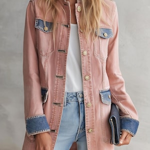 May include: A long-line pink denim jacket featuring contrasting blue denim panels on the chest pockets, cuffs, and collar. The jacket has a button-down front with metallic gold-toned buttons, long sleeves, and a structured collar, worn over a white top.