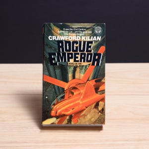 May include: A paperback book titled Rogue Emperor by Crawford Kilian, a novel of the Chronoplane Wars. The cover features a bright orange futuristic aircraft flying in front of classical columns, with text stating: It was the 21st Century against the 1st.
