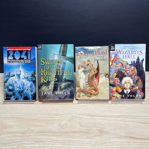 May include: Four paperback books by Jane Yolen arranged side-by-side. The titles are 2041, Sword of the Rightful King, Dragon's Blood, and Wizard's Hall. Each cover features distinct illustrations including a futuristic scene, a sword, a dragon, and a wizard.