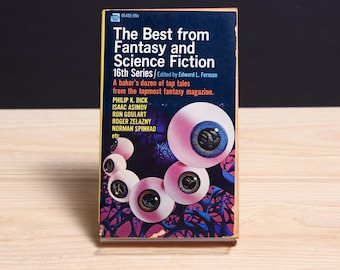 May include: A paperback book titled The Best from Fantasy and Science Fiction 16th Series edited by Edward L. Ferman. The dark blue cover features a graphic illustration of several floating human eyeballs against a purple and black abstract background.