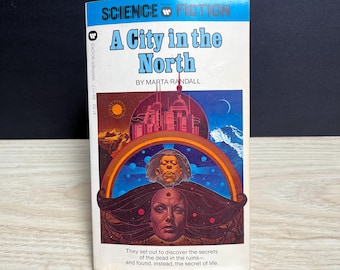 May include: A paperback science fiction book titled A City in the North by Marta Randall. The cover features a futuristic city, a crescent moon, a sun, and two faces, one with long dark hair, set against a blue, orange, and purple background.