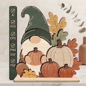 May include: A layered wooden gnome decoration featuring a dark green hat, a light wood-toned beard, and several orange and cream-colored pumpkins surrounded by autumn leaves. A vertical green bar on the left lists AI, SVG, EPS, PNG, DXF, and PDF.