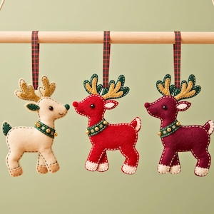 Finished red felt reindeer ornament with green and gold antlers, cream hooves, red pom-pom nose, plaid hanging loop and three gold jingle bells.